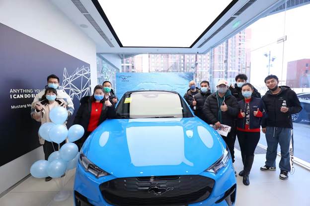 A group of people standing next to a blue carDescription automatically generated with medium confidence